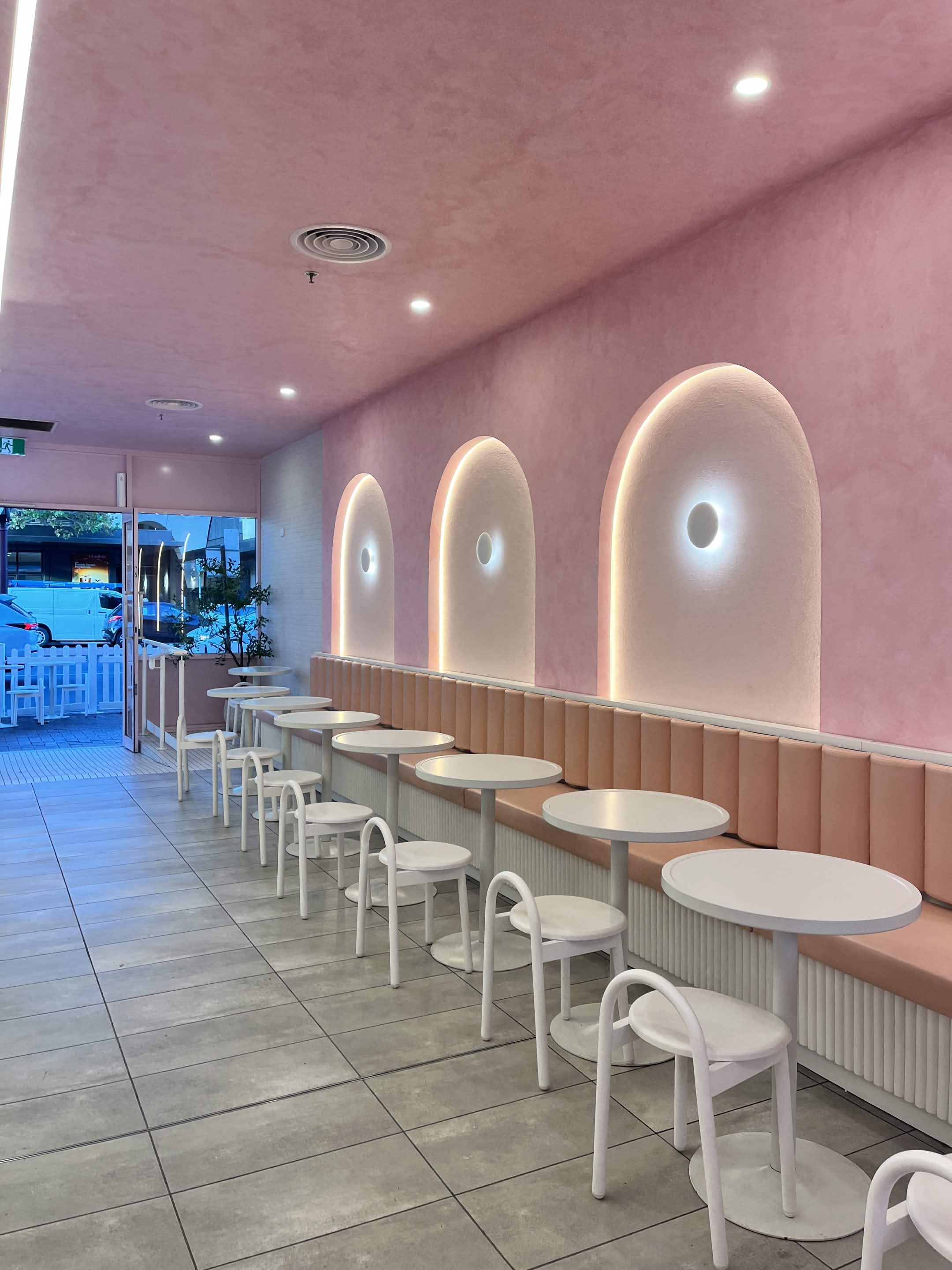 Fro Yoh interior with pink plaster arches, blush banquette seating and round white cafe tables