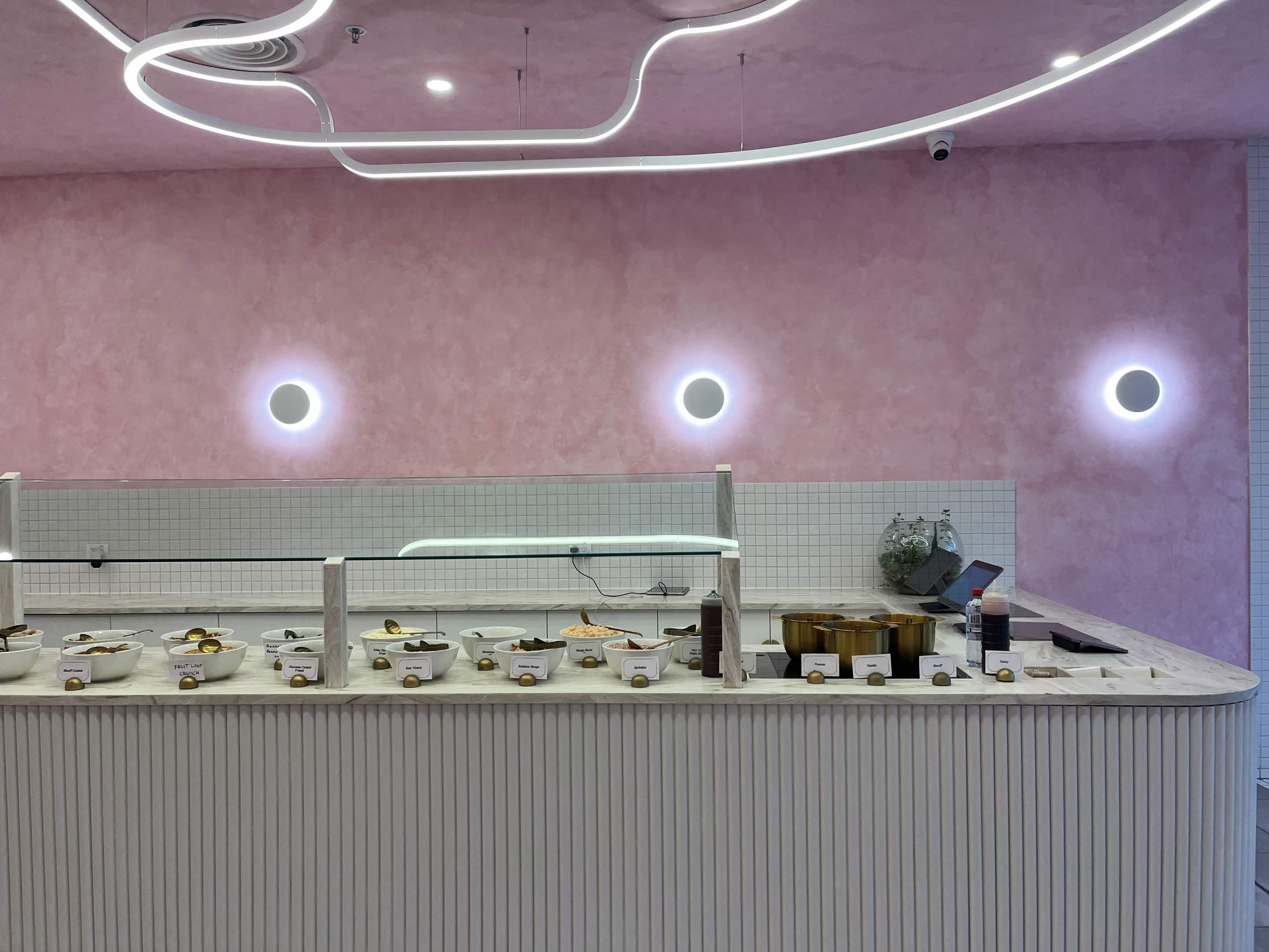 Self-serve toppings bar with labelled bowls on a marble counter at Fro Yoh